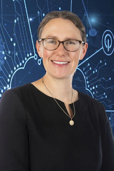 AA smiling woman with glasses and brown hair pulled back stands in front of a dark blue background with abstract white digital lines and binary code.